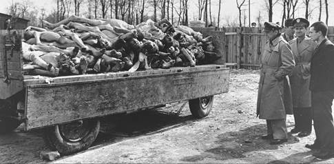 Three American radio journalists view a wagon full of corpses during a tour of the liberated Buchenwald concentration camp.

Pictured from left to right are, Lowell Thomas (NBC); Howard Barnes (WOR); and George Hamilton Combs (WHN).